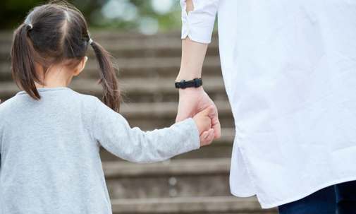 Child and adult holding hands on stairs